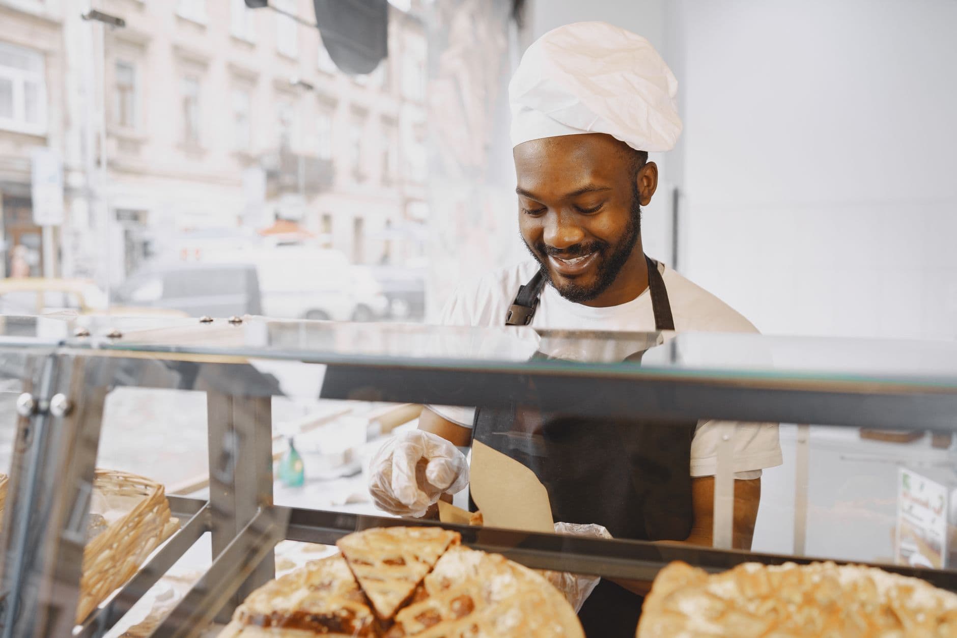 Baker in an apron boxing pastries behind a bakery display case