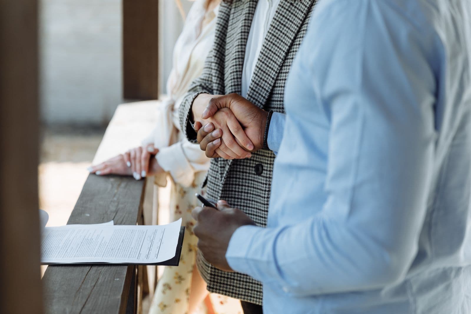 Two people shaking hands over a signed purchase agreement