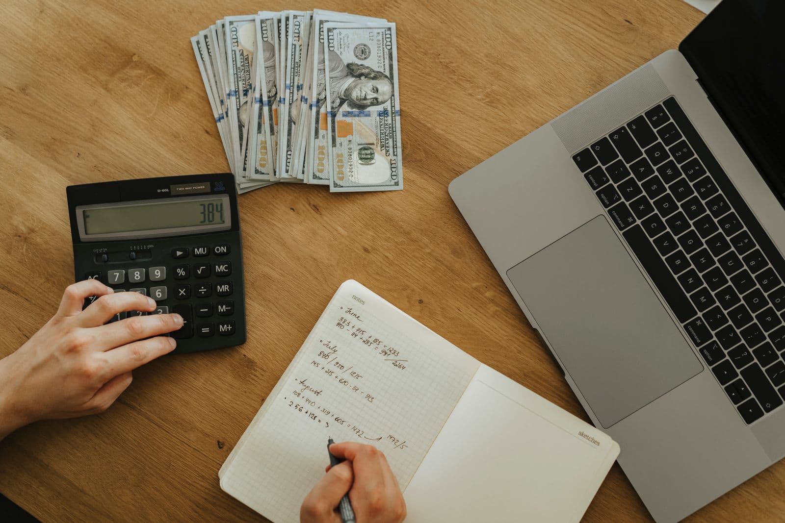 Business owner working through cash flow numbers with a calculator and laptop